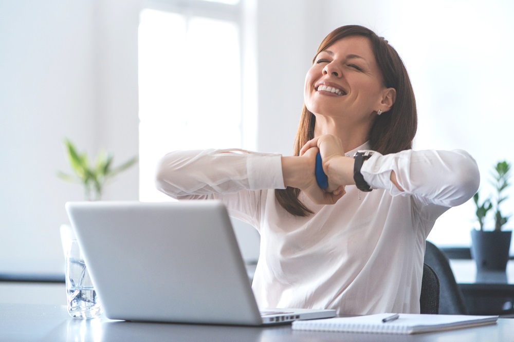 Excited woman working at desk in office. Using antistress ball.